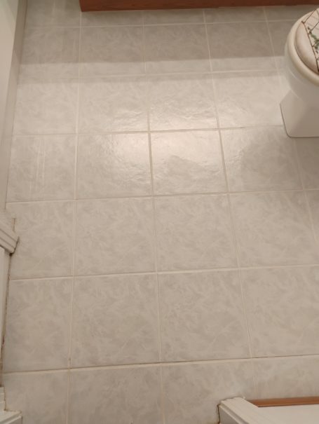 Tile & Grout Cleaning & Resealing White tiled bathroom floor with a visible toilet in the background.